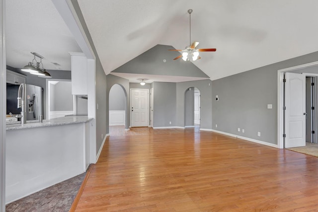 unfurnished living room featuring ceiling fan, lofted ceiling, and light hardwood / wood-style floors