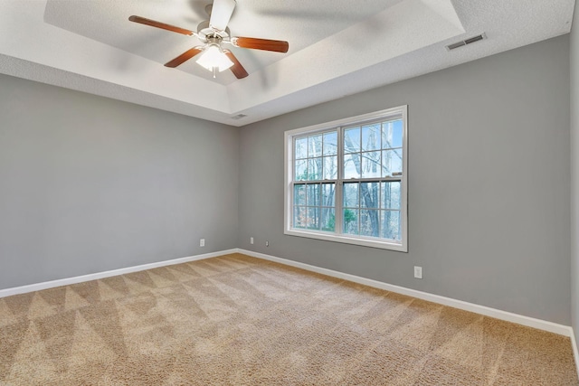 unfurnished room featuring ceiling fan, a tray ceiling, a textured ceiling, and carpet flooring