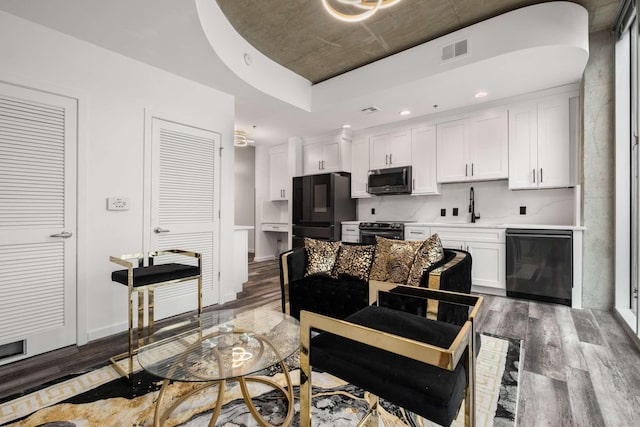 kitchen featuring dark hardwood / wood-style floors, white cabinets, a tray ceiling, and black appliances