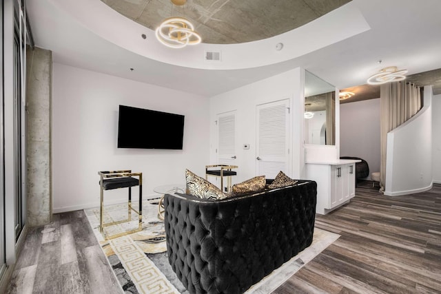 living room with dark hardwood / wood-style floors and a raised ceiling