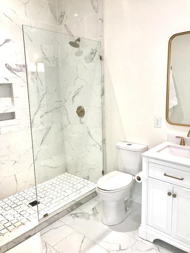 bathroom with vanity, toilet, and tiled shower