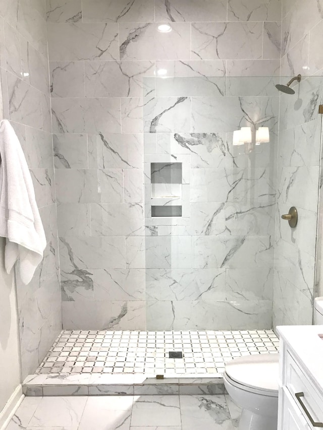 bathroom featuring vanity, toilet, and a tile shower