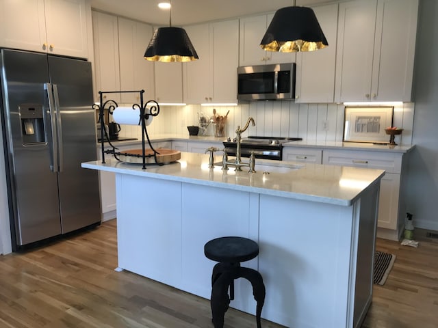 kitchen with a center island with sink, white cabinets, and appliances with stainless steel finishes