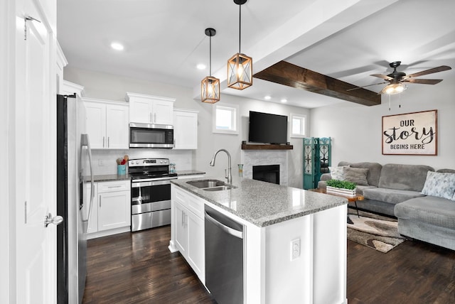 kitchen with sink, white cabinetry, light stone counters, stainless steel appliances, and a kitchen island with sink