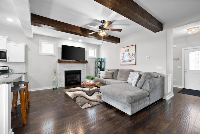 living room featuring beam ceiling, a stone fireplace, plenty of natural light, and dark hardwood / wood-style floors