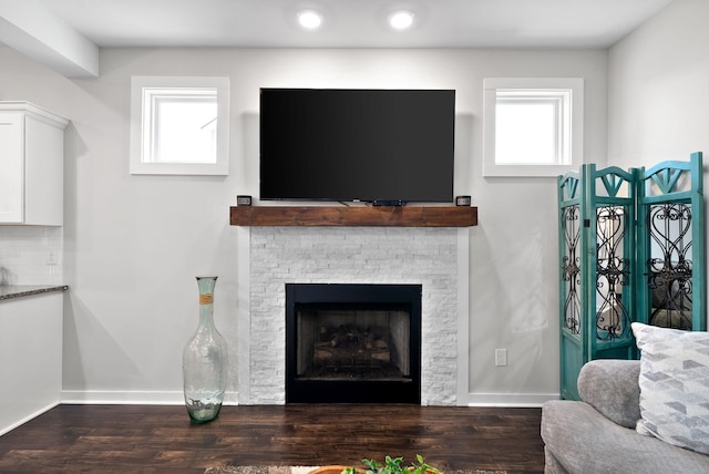 living room featuring a wealth of natural light, a fireplace, and dark hardwood / wood-style flooring