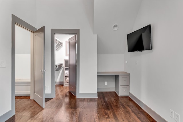 unfurnished bedroom with lofted ceiling, dark wood-type flooring, and built in desk