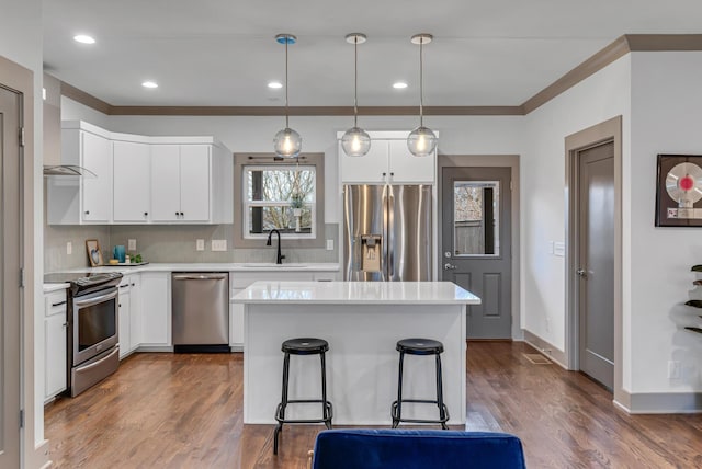 kitchen with appliances with stainless steel finishes, decorative light fixtures, sink, and white cabinets