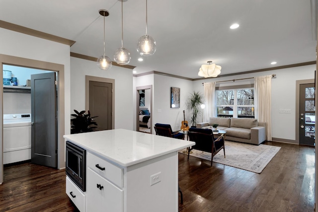 kitchen with dark hardwood / wood-style floors, a center island, stainless steel microwave, white cabinets, and decorative light fixtures