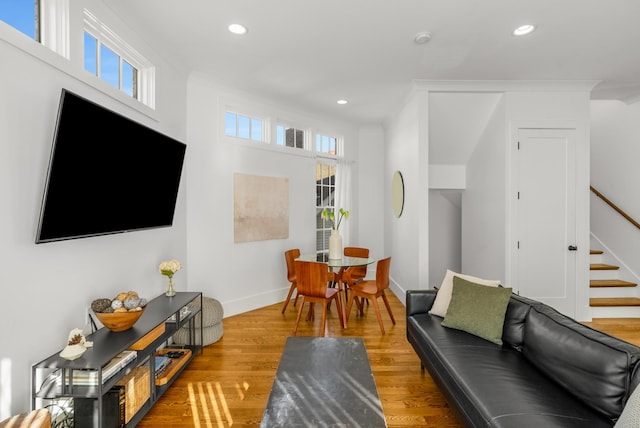 living room featuring wood-type flooring, ornamental molding, and plenty of natural light