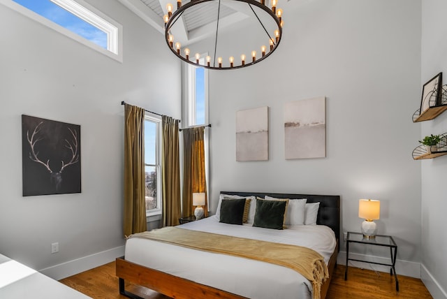 bedroom featuring hardwood / wood-style flooring, a towering ceiling, and a chandelier