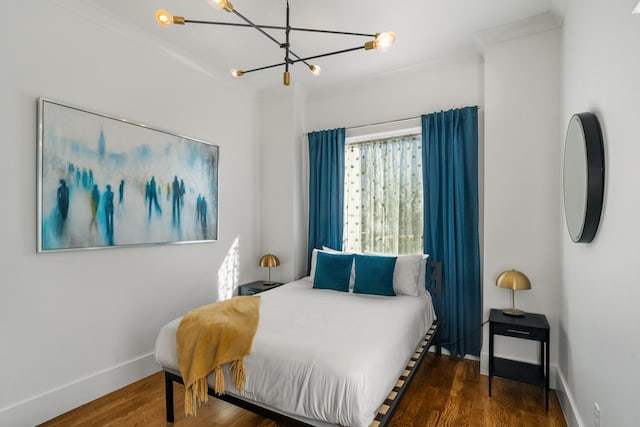 bedroom featuring crown molding, dark hardwood / wood-style flooring, and a chandelier