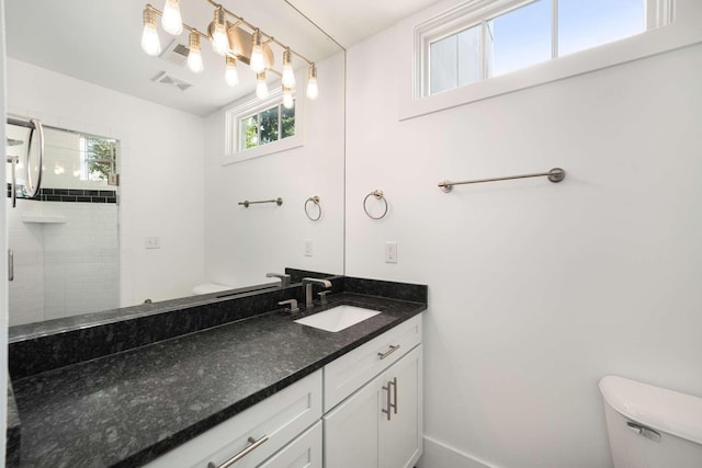 bathroom featuring vanity, toilet, and a shower with door