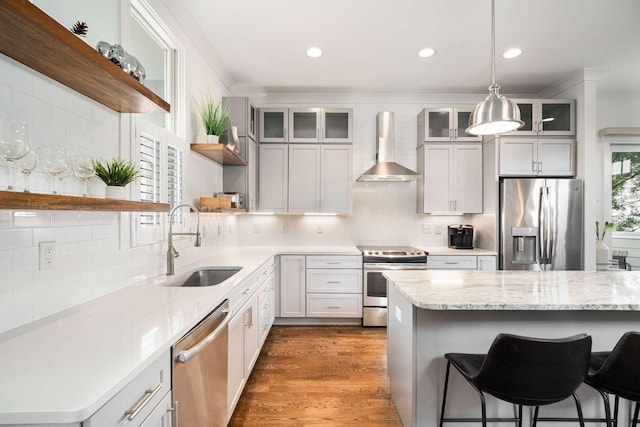 kitchen with wall chimney exhaust hood, sink, a breakfast bar area, stainless steel appliances, and white cabinets