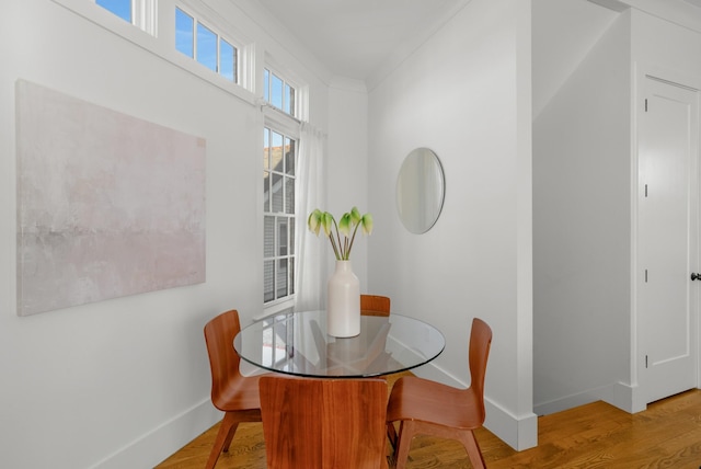 dining space with crown molding and light hardwood / wood-style floors