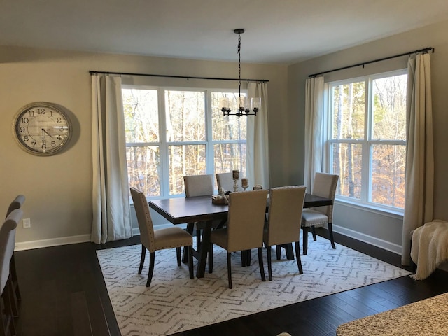 dining area featuring a chandelier, baseboards, and wood finished floors