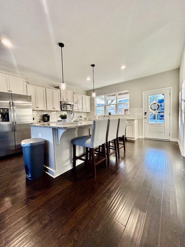 kitchen with dark wood-style floors, appliances with stainless steel finishes, backsplash, and white cabinets