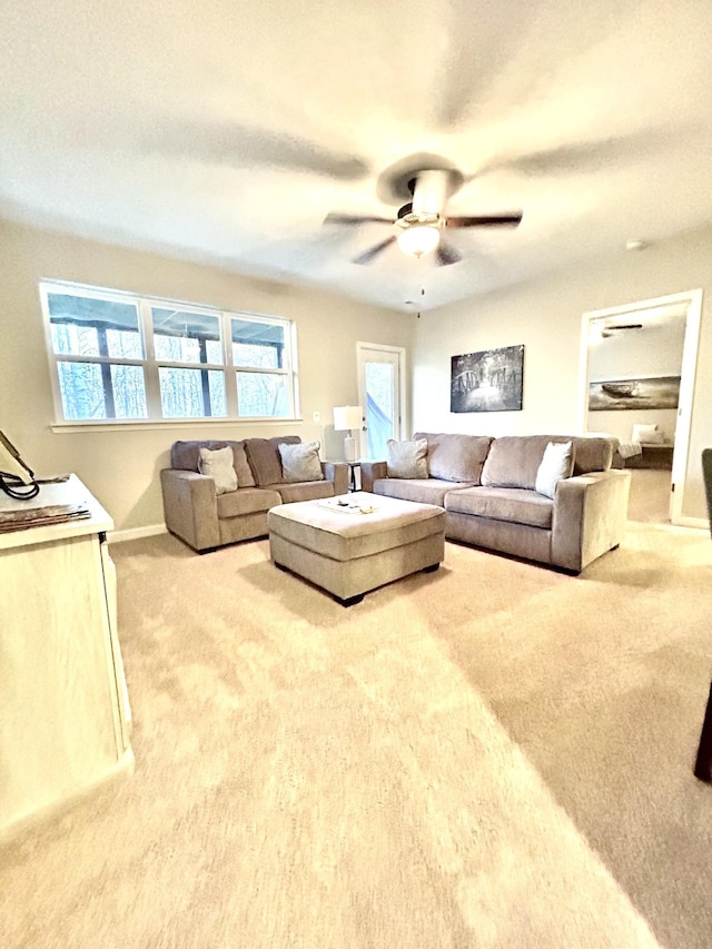 living area featuring carpet floors, baseboards, and a ceiling fan