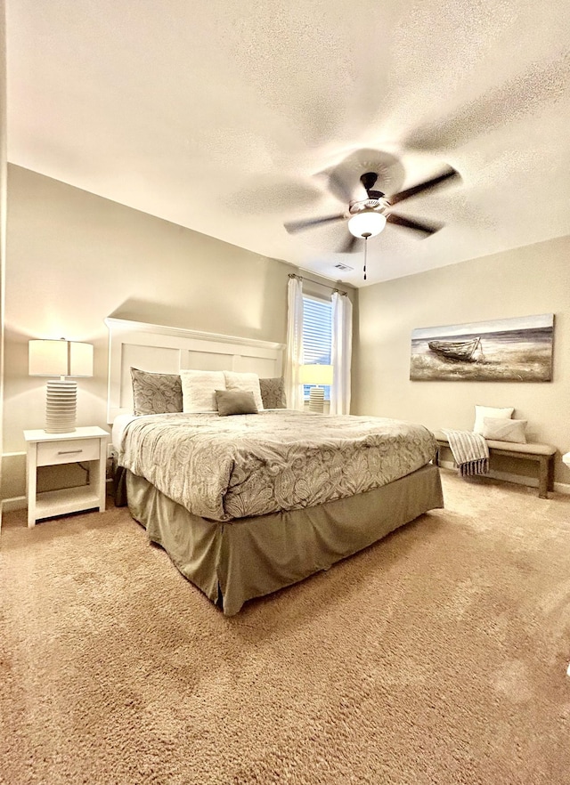 carpeted bedroom with ceiling fan and a textured ceiling