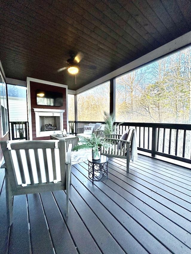 wooden deck with a ceiling fan and exterior fireplace