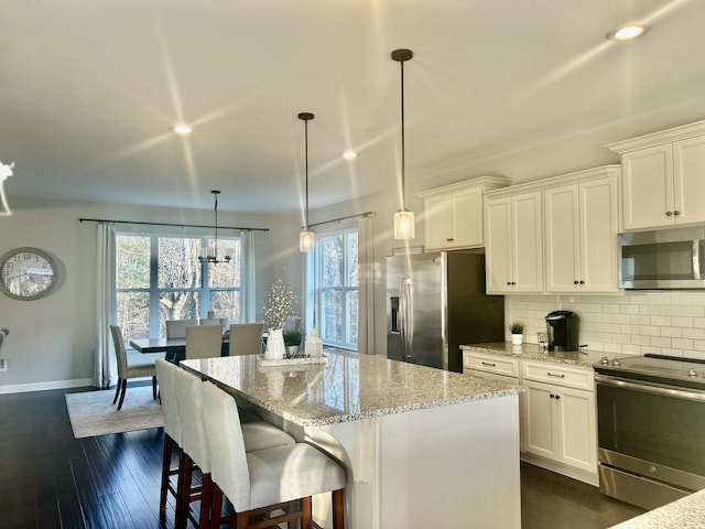 kitchen featuring tasteful backsplash, white cabinetry, stainless steel appliances, and a center island