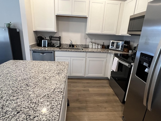 kitchen with sink, light stone countertops, white cabinets, and appliances with stainless steel finishes