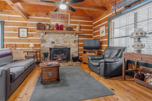 living room with wood ceiling, hardwood / wood-style flooring, vaulted ceiling with beams, wooden walls, and a stone fireplace