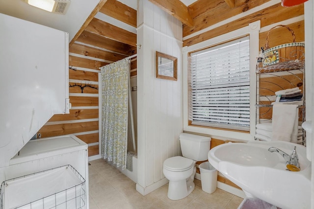 full bathroom featuring shower / bathtub combination with curtain, sink, tile patterned flooring, toilet, and wood walls