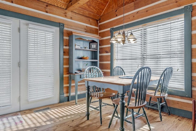 dining space with vaulted ceiling, wood-type flooring, and an inviting chandelier