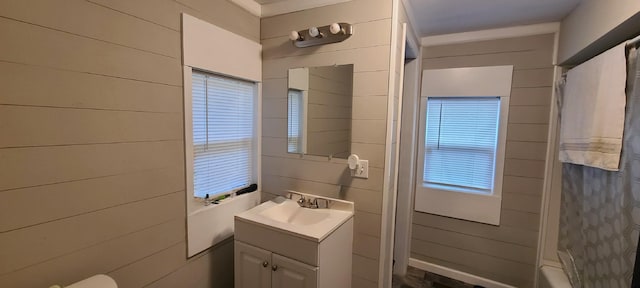 bathroom featuring vanity, wooden walls, and shower / bath combo with shower curtain