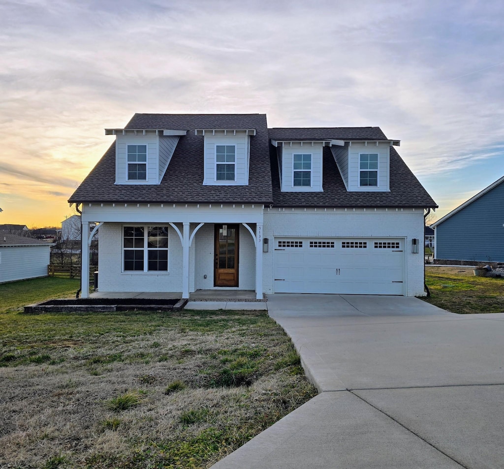 cape cod home featuring a garage and covered porch