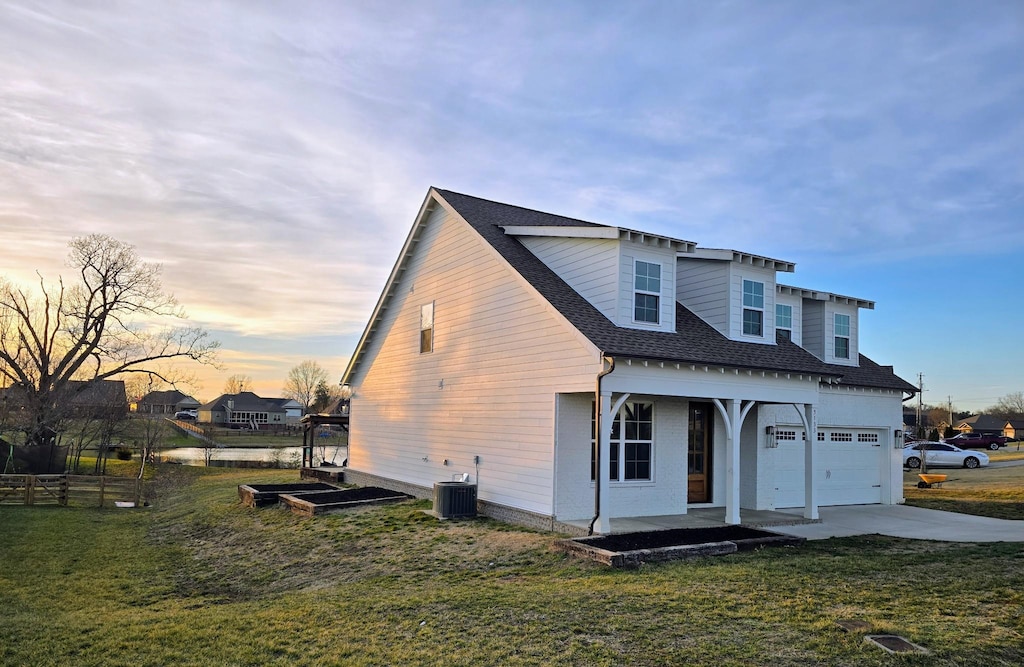 view of front of house with a garage, central AC, and a lawn