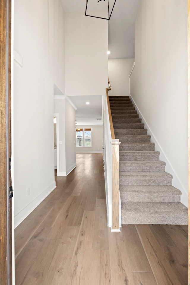 stairs with hardwood / wood-style floors and a towering ceiling