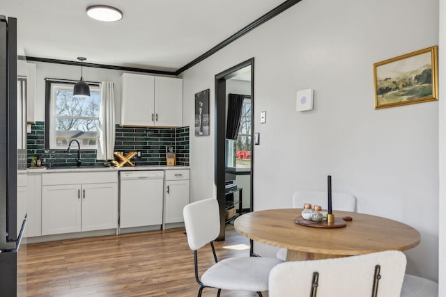 kitchen featuring white cabinetry, white dishwasher, sink, and hanging light fixtures