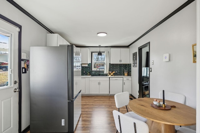 kitchen with white cabinetry, dishwasher, sink, and stainless steel refrigerator