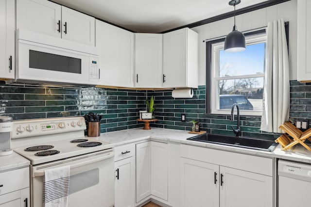 kitchen with sink, white appliances, white cabinetry, light stone counters, and decorative light fixtures