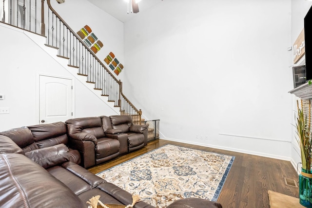 living room featuring dark hardwood / wood-style floors, ceiling fan, and a high ceiling