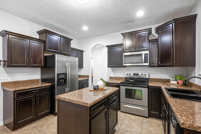 kitchen with stainless steel appliances, a center island, sink, and dark brown cabinets