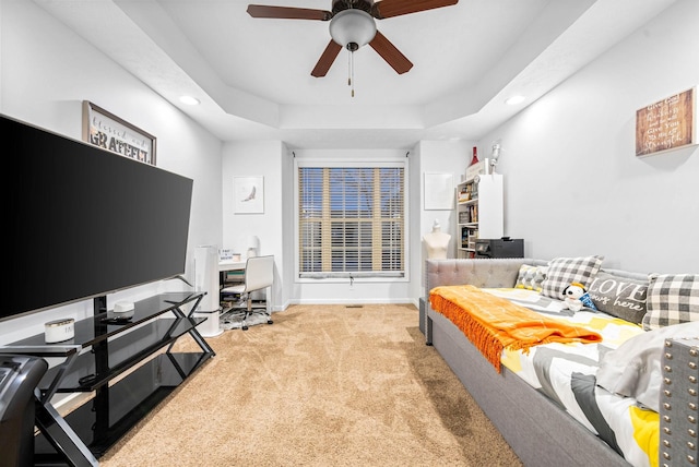 carpeted bedroom with a tray ceiling and ceiling fan