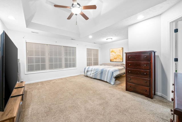 carpeted bedroom featuring a tray ceiling and ceiling fan