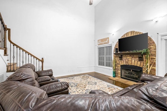 living room featuring hardwood / wood-style flooring, a fireplace, and a high ceiling