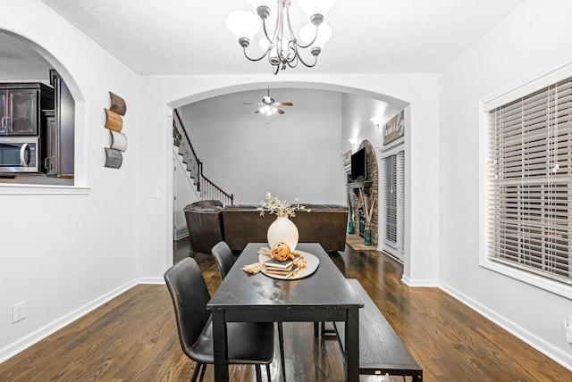 dining area with dark hardwood / wood-style flooring and ceiling fan with notable chandelier