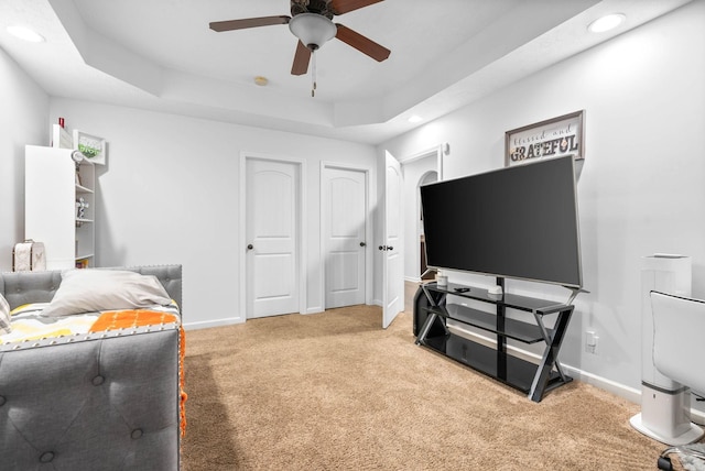 bedroom with ceiling fan, a raised ceiling, and carpet floors