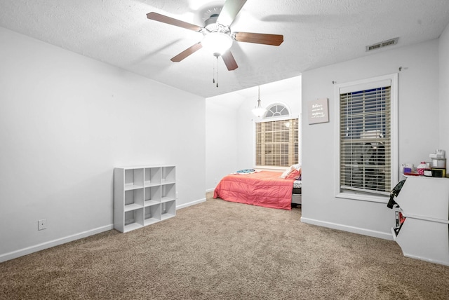 carpeted bedroom featuring ceiling fan and a textured ceiling