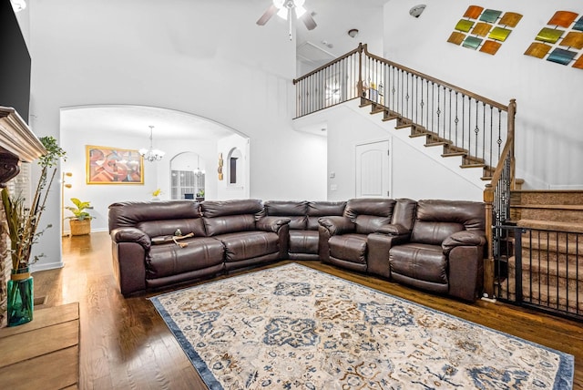 living room with ceiling fan with notable chandelier, dark hardwood / wood-style floors, and a high ceiling