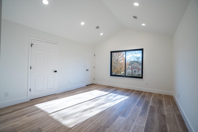 unfurnished room with wood-type flooring and high vaulted ceiling