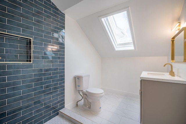 bathroom with vanity, toilet, and vaulted ceiling with skylight