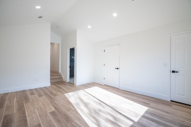 empty room featuring vaulted ceiling and light hardwood / wood-style flooring