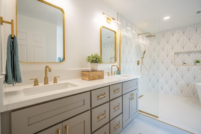 bathroom with a tile shower, vanity, and tile patterned floors