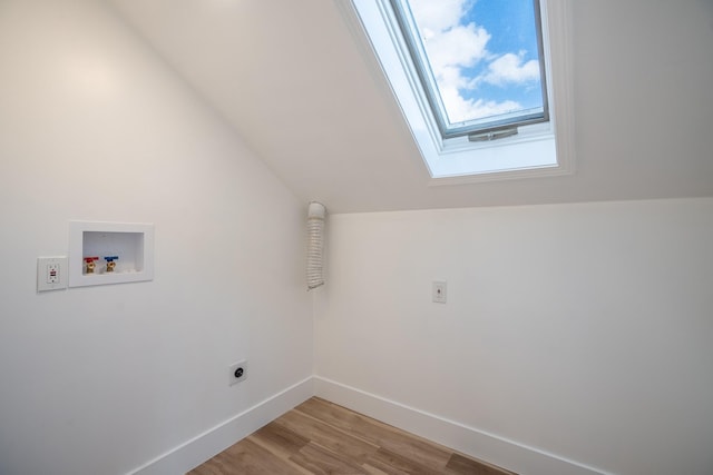 washroom with electric dryer hookup, washer hookup, a skylight, and light hardwood / wood-style floors